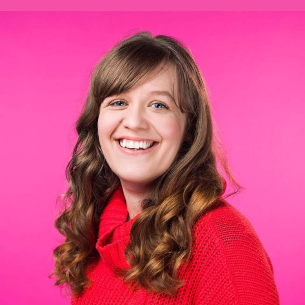 Head shot of Kay on a side angle, smiling with curly wavy hair